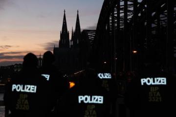 Polizisten warten auf ihren Einsatz vor dem dunklen Kölner Dom bei der Kögida/Pegida ("Patriotische Europäer gegen die Islamisierung des Abendlandes") Demonstration in Köln am 5. Januar 2015. Der Dom wurde zur Zeit der Demonstration nicht beleuchtet und blieb dunkel.