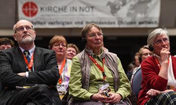 Zuschauer beim Kongress von "Kirche in Not" am 14. März 2015 in Würzburg. Im Hintergrund hängt ein Banner mit dem Logo von "Kirche in Not".