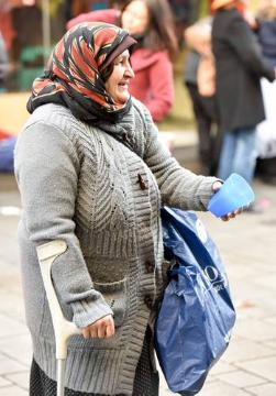 Eine alte Frau mit Kopftuch und Krücke bettelt am 16. Februar 2015 in der Düsseldorfer Altstadt mit einem Becher um Geld.