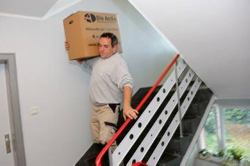 Haushaltsauflösung durch Mitarbeiter der Arche in Bonn am 21. September 2015. Die Arche in Bonn bietet berufliche Reintegration von Langzeitarbeitslosen und behinderten Menschen. Bild: Ein Mitarbeiter trägt einen Karton die Treppe runter.