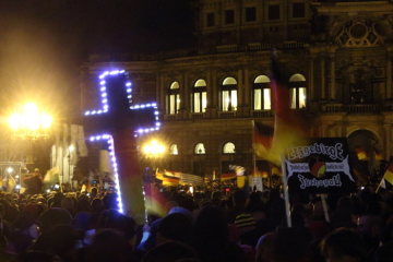 PEGIDA-Anhänger demonstrieren am 22. Dezember 2014 auf dem Theaterplatz in Dresden gegen die "Islamisierung des Abendlandes". Dabei halten sie ein leuchtendes Kreuz in die Höhe.